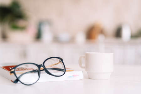 Book with glasses and coffee are on the white tableの写真素材