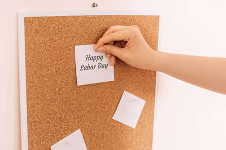 Womans hand hangs a sticker saying happy labor day