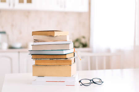 Stack of books with glasses standing on a table in front of the kitchenの写真素材