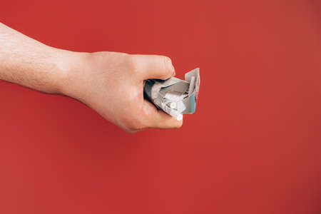 Hand crushes pack of cigarettes against red backgroundの写真素材