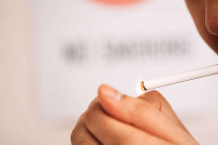 Man lights cigarette against blurred backgroundの写真素材