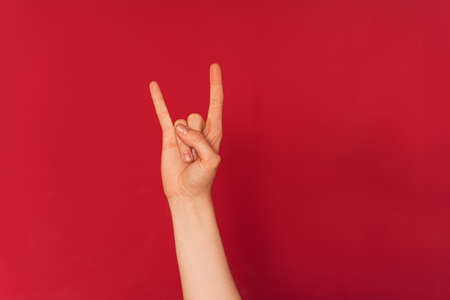 Womans hand shows rock and roll symbol against red backgroundの写真素材