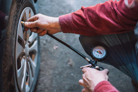 Mechanic checking tire pressure with pneumatic compressorの写真素材