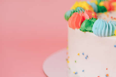 Background of white cake with colorful cream against pink backgroundの写真素材