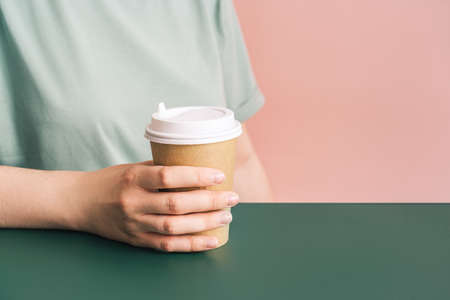 Girl with glass of coffee in her hands sits at green tableの写真素材