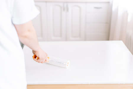 Girl paints the table with white paint table with rollerの写真素材
