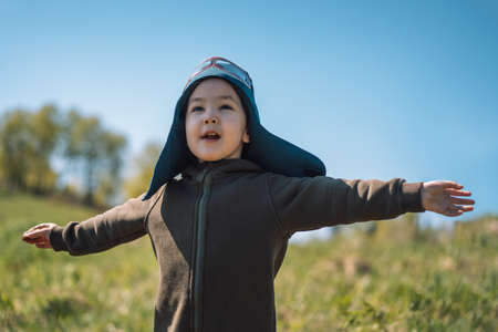Girl with outstretched arms in pilot suit plays outdoorsの写真素材