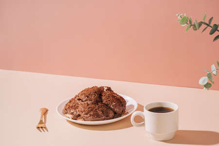 Cake on plate with golden fork and cup of coffee on the table against pink background