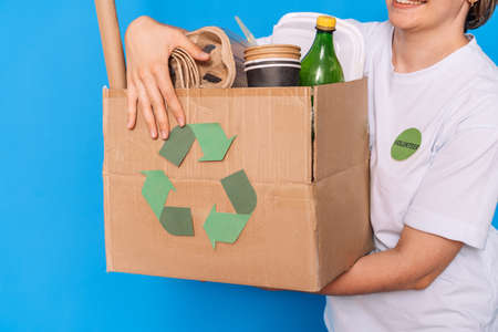 Girl carries in her hands a box with garbage for recyclingの写真素材