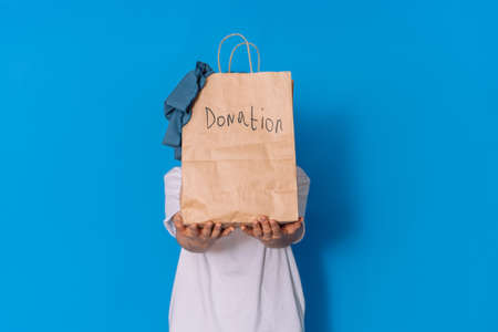 Girl holding paper bag with clothes in front of her for donation