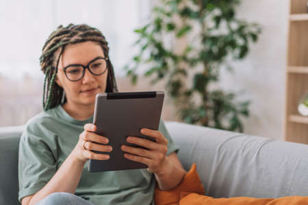 Girl with glasses reading a book on a tabletの写真素材