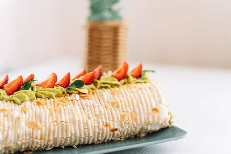 Meringue roll with strawberries on a blue plate near the basketの写真素材