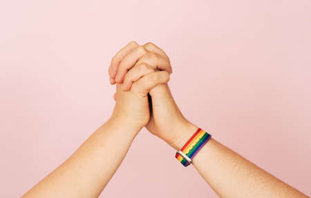 Two female hands hold each other against a pink backgroundの写真素材