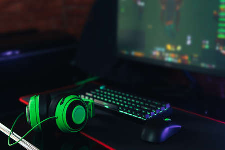 Gaming accessories with green backlight in front of the monitorの写真素材