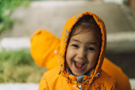 Children in yellow rain suits standing in the rain