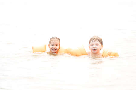 Children swim in the sea with armbands on their hands