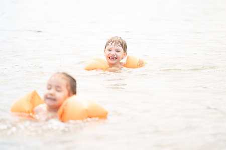 Children swim in the sea with swim wings on their handsの写真素材