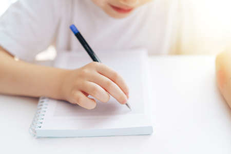 Child writes with a pen in a notebook with ringsの写真素材