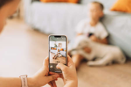 The girl takes a picture on the phone of a child with a puppyの写真素材