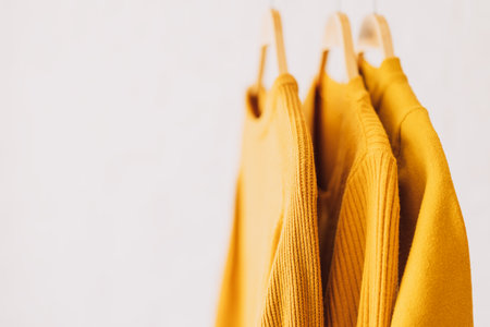 Yellow sweatshirts hang on wooden hangersの写真素材