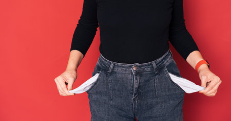 Lady turned out her empty pockets against red backgroundの写真素材
