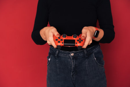 Woman holding gamepad in her hands against red background