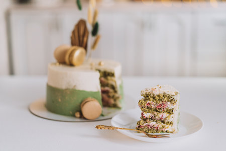 Cutaway spinach cake with macarons on white tableの写真素材