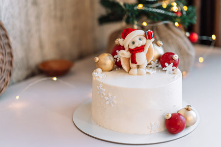 White Christmas cake with caramel bunny and balls in front of the lights from the garlandsの写真素材