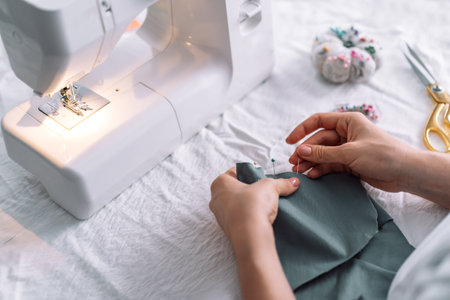 Lady fixes fabric with needles in front of a sewing machineの写真素材