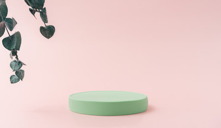 Round green podium next to branch of eucalyptus against pink backgroundの写真素材