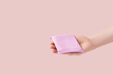 Sanitary pad in female hand against pink backgroundの写真素材