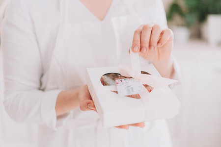 Girl in a white uniform holding chocolate-covered strawberries in a gift boxの写真素材