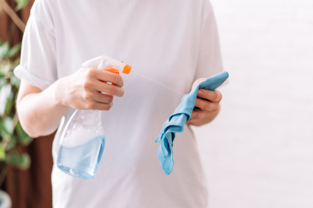 Lady spraying detergent on a blue rag