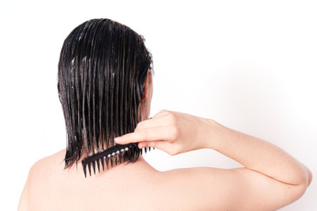 Lady applying hair mask with comb against white backgroundの写真素材