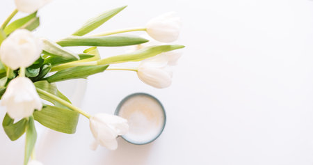 Bouquet of white tulips with cup of coffee on white backgroundの写真素材