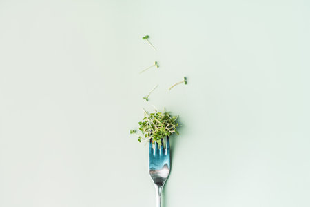 Young sprouts of microgreens on fork on green backgroundの写真素材