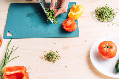 Lady cutting green onion for vegetable salad with microgreensの写真素材