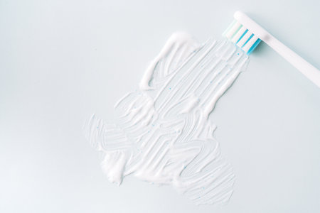 Smeared toothpaste with electric toothbrush over blue backgroundの写真素材