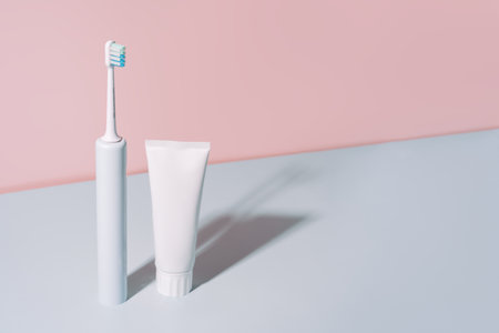 Electric toothbrush with toothpaste against a blue-pink backgroundの写真素材