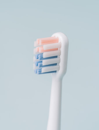 Vertical photo of an electric toothbrush head in profile against blue backgroundの写真素材