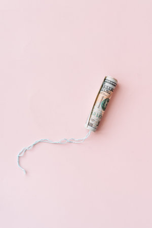 Tampon wrapped in hundred dollar bill on pink backgroundの写真素材