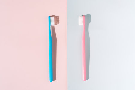 Blue and pink toothbrush on pink and blue background under hard lightの写真素材