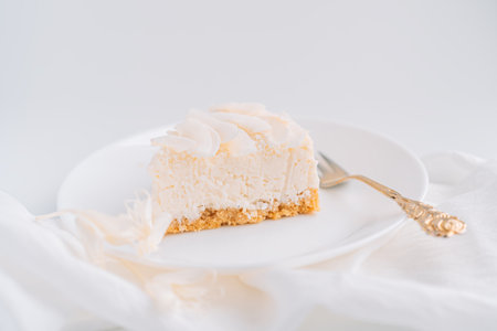 White cheesecake with coconut flavor on plate with fork on white backgroundの写真素材