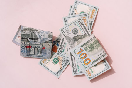 One hundred dollar bills and tenge on a pink backgroundの写真素材