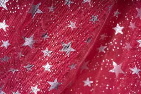 Transparent tulle background with glittering stars on red tulle