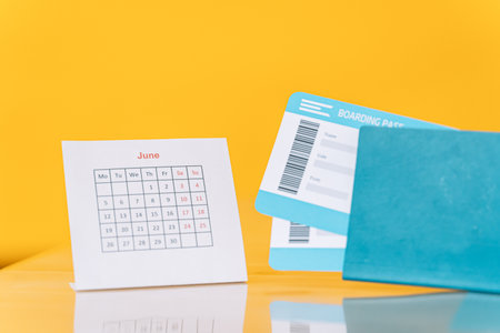 Air tickets in the passport next to the June calendar against yellow background