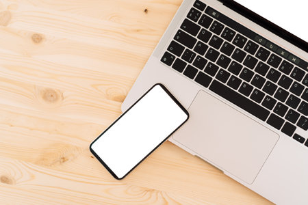 Smartphone and laptop with white screens for text or advertising on a wooden tableの写真素材