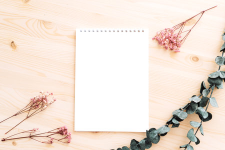 Empty white notepad with dried flowers on wooden table