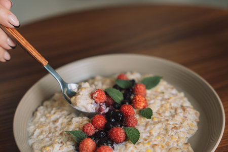 Oatmeal with raspberries and currants in a white cup with a spoonの写真素材