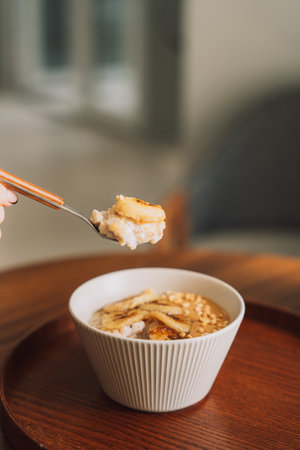 Oatmeal with banana slices in a white cup with a spoon